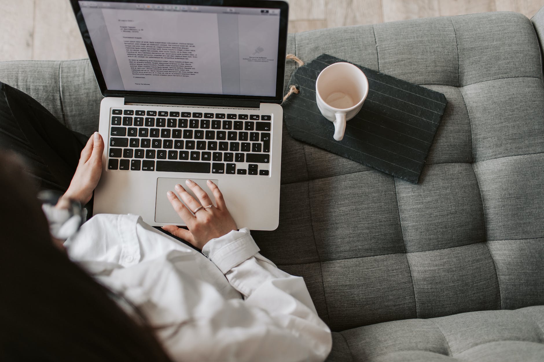 crop woman using laptop on sofa at home